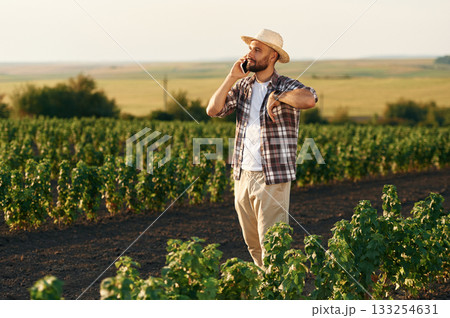 Having conversation by phone. Farmer is on the agricultural field 133254631