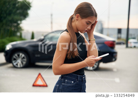 Trying to catch the signal and help by phone. Woman's car is broken, accident, standing outdoors 133254849