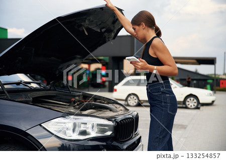 Woman's car is broken, accident, standing outdoors 133254857