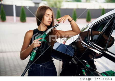 Standing and posing. A young woman at a gas station with her car Standing and posing. A young woman at a gas station with her car 133254903