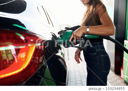 Process of refilling. A young woman at a gas station with her car 133254955