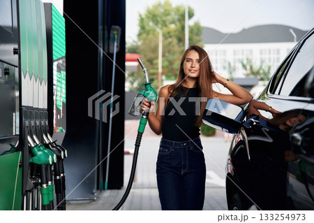 Ready to refill the automobile. A young woman at a gas station with her car 133254973