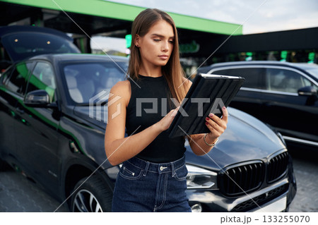 Digital tablet in hands. Woman is near her car outdoors 133255070