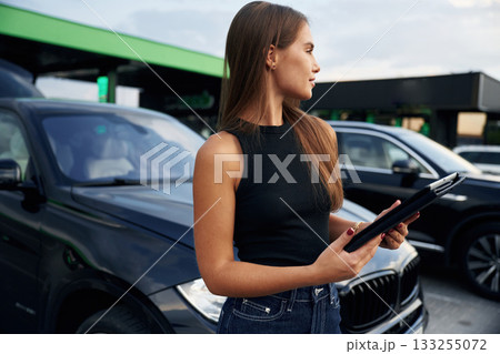 Digital tablet in hands. Woman is near her car outdoors 133255072