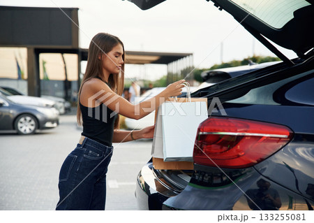 Trunk is opened. Woman is near her car outdoors 133255081