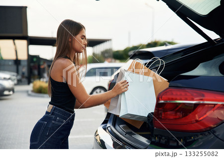 Trunk is opened. Woman is near her car outdoors 133255082