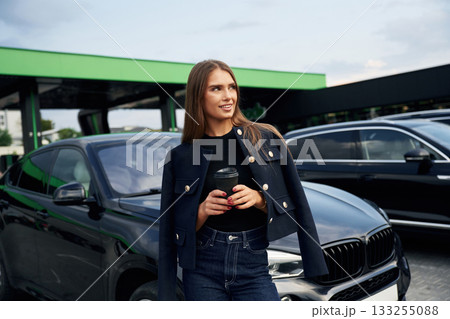 Daily coffee. A young woman at a gas station with her car Daily coffee. A young woman at a gas station with her car 133255088