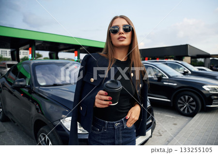 In sunglasses. A young woman at a gas station with her car In sunglasses. A young woman at a gas station with her car 133255105