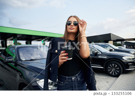 In sunglasses. A young woman at a gas station with her car In sunglasses. A young woman at a gas station with her car 133255106