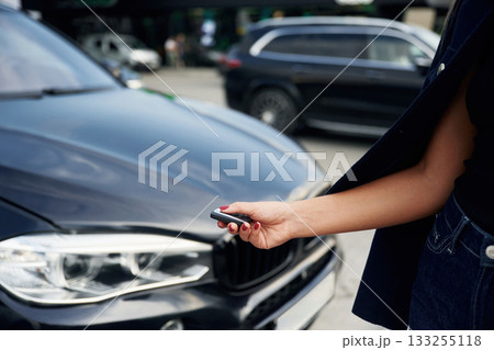 Focused close up view of woman hand that is holding key in front of the car Focused close up view of woman hand that is holding key in front of the car 133255118