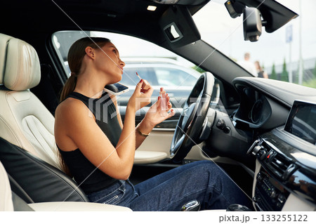 Side view, talking by phone. Woman is sitting in the car 133255122