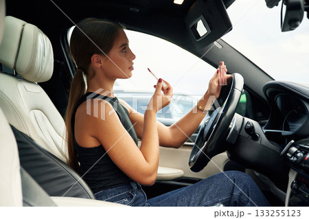 Side view, talking by phone. Woman is sitting in the car 133255123