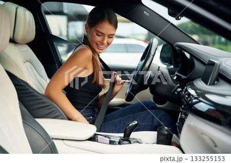 Wearing safety belt. Woman is sitting in the car 133255153
