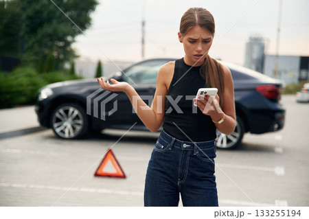 Trying to catch the signal and help by phone. Woman's car is broken, accident, standing outdoors 133255194