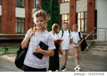 Portrait of girl that is standing in front of her friends. Kids are near the school together, pupils 133255426