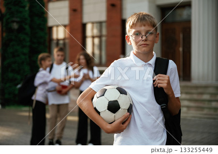 Boy is with soccer ball. Kids are near the school together, pupils 133255449