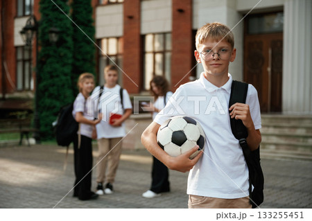 Boy is with soccer ball. Kids are near the school together, pupils 133255451