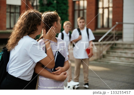 Gossip about the boys. Kids are near the school together, pupils 133255457