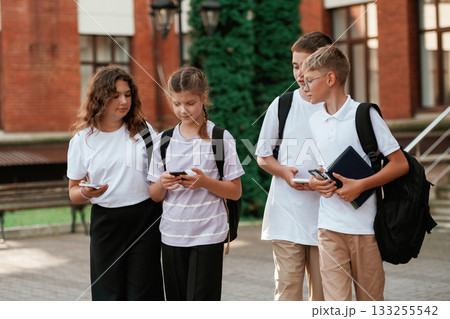 Smartphones in hands. Kids are near the school together, pupils 133255542