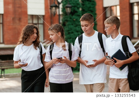 Smartphones in hands. Kids are near the school together, pupils 133255543