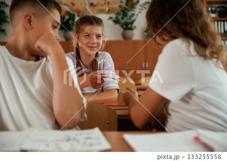 Taking the cheat sheet. Pupils, kids in the classroom together Taking the cheat sheet. Pupils, kids in the classroom together 133255558