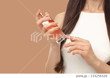Woman with long hair holds a perfume bottle in an elegant setting 133256326