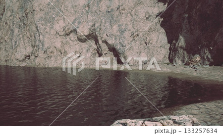 Gentle waves lap against a sandy shore, while impressive cliffs rise majestically in the background. This peaceful scene captures the beauty of nature at a secluded spot during the day. Gentle waves lap against a sandy shore, while impressive cliffs rise majestically in the background. This peaceful scene captures the beauty of nature at a secluded spot during the day. 133257634