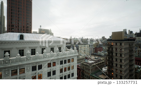 Amidst tall buildings, a stunning urban landscape unfolds, revealing intricate designs and a moody sky. The scene captures city life and architectural beauty in the afternoon light. 133257731