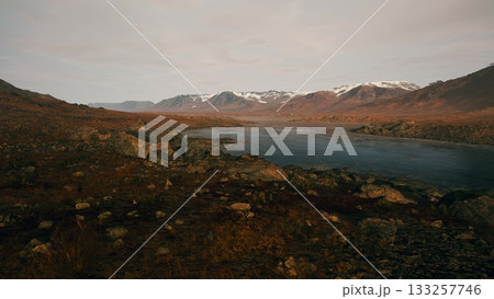 Expansive view of a serene river flowing through a valley surrounded by majestic mountains. The sky glows softly as dusk settles, casting stunning colors over the landscape. Expansive view of a serene river flowing through a valley surrounded by majestic mountains. The sky glows softly as dusk settles, casting stunning colors over the landscape. 133257746