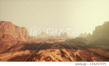 A breathtaking desert landscape features rocky formations stretching towards the horizon. The warm hues of the sky create a serene atmosphere as the sun begins to set. 133257775