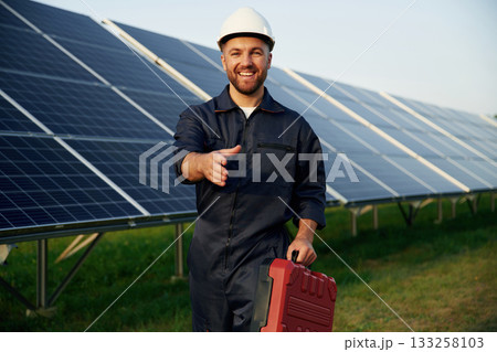 Red case in hand. Man is working with solar panels outdoors at daytime 133258103