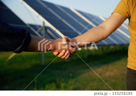 Close up view of handshake against solar panels outdoors 133258185