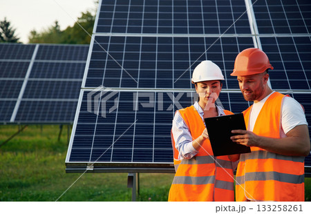 Man and woman, workers are near solar panels, in uniform 133258261