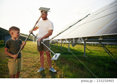 Time to clean the surface. Father with his little son are together near the solar panels Time to clean the surface. Father with his little son are together near the solar panels 133258465