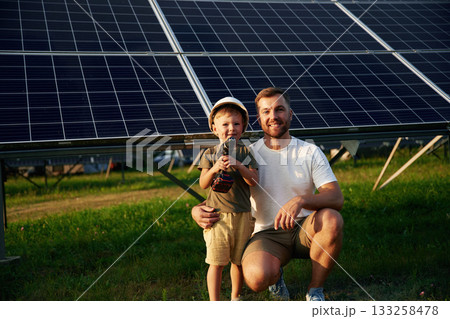 Posing with drill in hands. Father with his little son are together near the solar panels 133258478