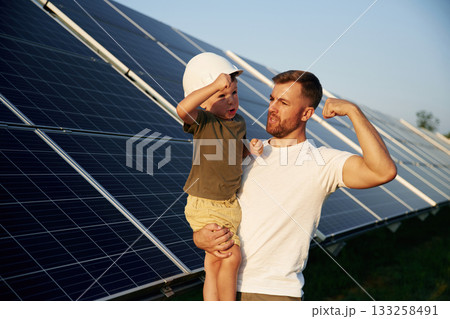 White hard hat. Father with his little son are together near the solar panels White hard hat. Father with his little son are together near the solar panels 133258491