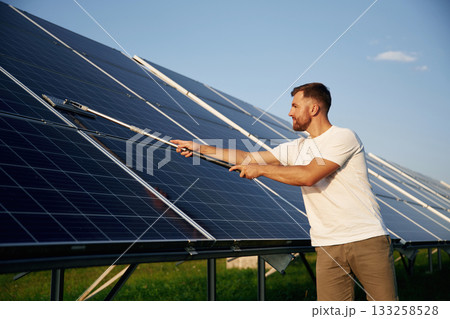 Professional cleaning. Man is working with solar panels outdoors at daytime 133258528
