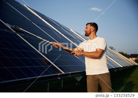 Professional cleaning. Man is working with solar panels outdoors at daytime 133258529
