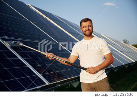 Mop in hands. Man is working with solar panels outdoors at daytime Mop in hands. Man is working with solar panels outdoors at daytime 133258530