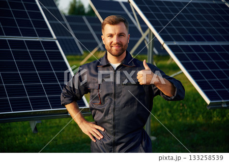 Portrait, standing with arms crossed. Man is working with solar panels outdoors at daytime 133258539