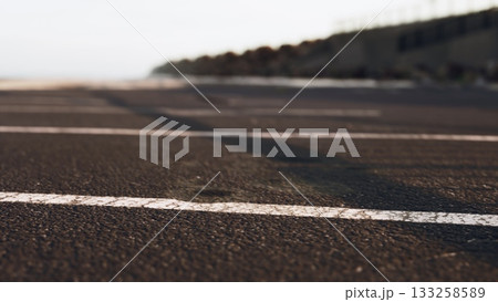 The scene captures a deserted road by the ocean, showcasing a quiet atmosphere. Gentle waves can be seen in the background, hinting at the serene beauty of twilight. 133258589
