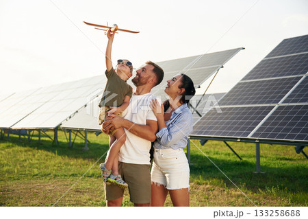 Family is together. Father, mother and little son are outdoors near solar panels Family is together. Father, mother and little son are outdoors near solar panels 133258688