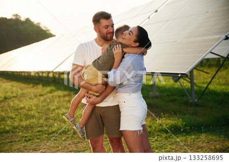 Embracing each other. Father, mother and little son are outdoors near solar panels 133258695