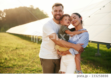 Embracing each other. Father, mother and little son are outdoors near solar panels 133258698