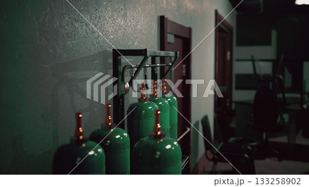 In a dimly lit gym, green gas tanks are neatly arranged on a wall. The atmosphere hints at intense weightlifting sessions and strong determination from dedicated athletes. In a dimly lit gym, green gas tanks are neatly arranged on a wall. The atmosphere hints at intense weightlifting sessions and strong determination from dedicated athletes. 133258902