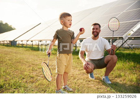 Game of badminton. Father with his little son are together near the solar panels 133259026