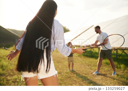 Active weekend, badminton. Father, mother and little son are outdoors near solar panels 133259027