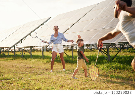 Active weekend, badminton. Father, mother and little son are outdoors near solar panels 133259028