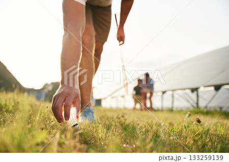 Tranquil, playing badminton. Father, mother and little son are outdoors near solar panels Tranquil, playing badminton. Father, mother and little son are outdoors near solar panels 133259139