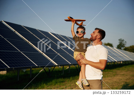 Aviator glasses and toy plane. Father with his little son are together near the solar panels 133259172